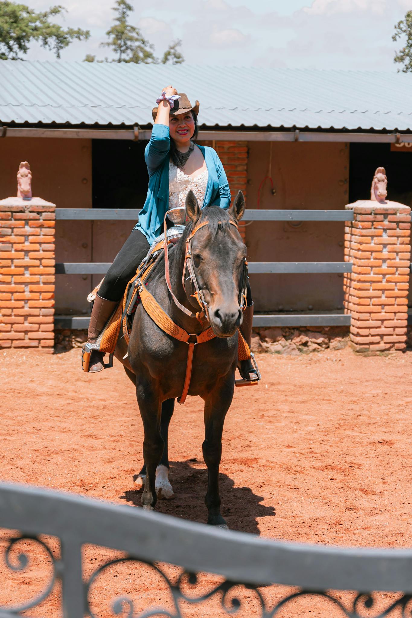 A young woman in a cowboy hat enjoys horseback riding outdoors on a ranch.
