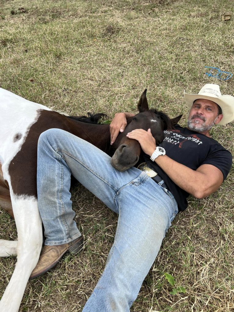 Ty Nordic lying down with horse.